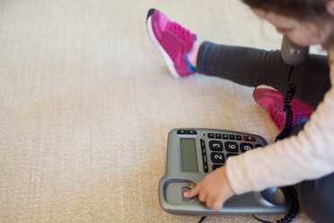 Kleines Mädchen spielt mit dem Telefon und sitzt auf dem Teppich - LSF000020