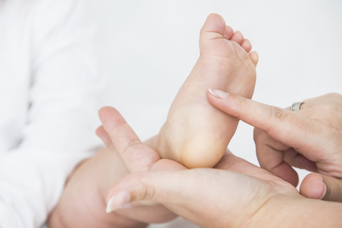 Mother's hand tickling baby's sole of foot stock photo