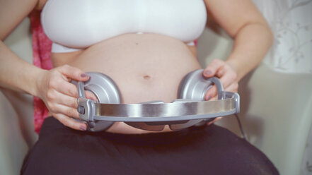 Pregnant Woman Holding Headphones Near Belly, Playing Melody To Baby In  Womb Stock Photo by Prostock-studio