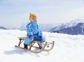 Germany, Tegernsee, Wallberg, smiling little boy sitting on sledge - EDF000133