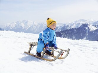 Germany, Tegernsee, Wallberg, smiling little boy sitting on sledge - EDF000134
