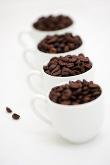 Vier weiße Tassen mit Kaffeebohnen auf weißem Grund - LSF000033