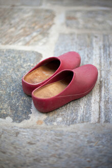 Pair of red rubber gardening shoes on stone floor - LSF000026