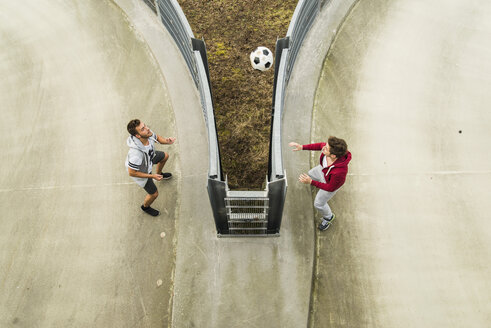 Zwei junge Männer köpfen einen Fußball über den Zaun - UUF003671