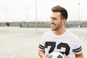 Portrait of smiling young man with soccer ball outdoors - UUF003675