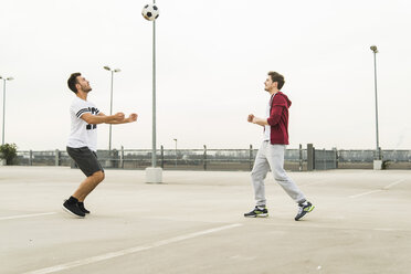 Zwei junge Männer spielen Fußball auf dem Parkdeck - UUF003677