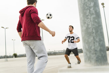 Zwei junge Männer spielen Fußball auf dem Parkdeck - UUF003680