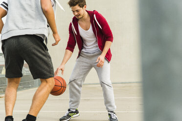 Zwei junge Männer spielen Basketball auf dem Parkdeck - UUF003683