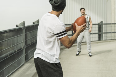 Zwei junge Männer spielen mit einem Fußball auf der Straße - UUF003695