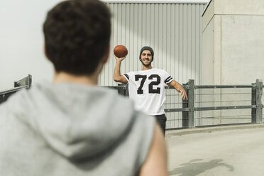 Zwei junge Männer spielen mit einem Fußball auf der Straße - UUF003696