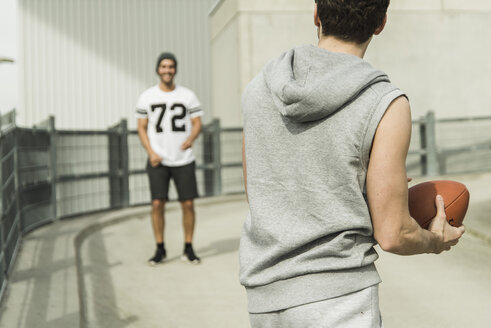 Zwei junge Männer spielen mit einem Fußball auf der Straße - UUF003698