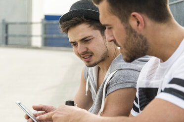 Zwei Freunde schauen auf ihr Mobiltelefon - UUF003700