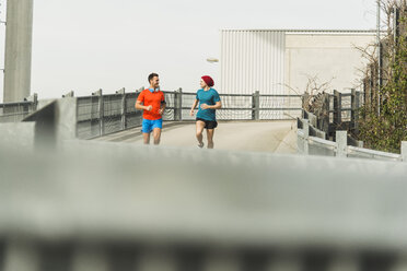 Zwei junge Männer joggen auf einer Brücke - UUF003703