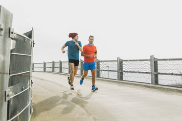 Zwei junge Männer joggen auf einer Brücke - UUF003705