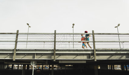 Zwei junge Männer joggen auf einer Brücke - UUF003706