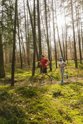 Zwei junge Männer joggen auf einem Waldweg - UUF003715