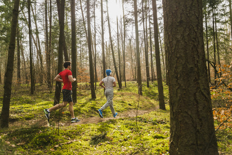 Zwei junge Männer joggen auf einem Waldweg, lizenzfreies Stockfoto