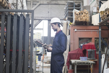 Warehouseman in storehouse holding clipboard - SGF001426