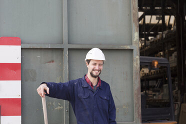 Smiling worker outside factory hall - SGF001416