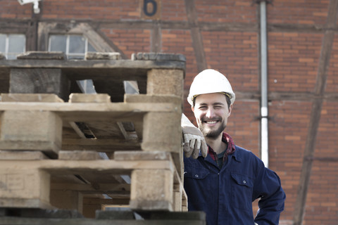 Lächelnder Arbeiter hinter Paletten, lizenzfreies Stockfoto