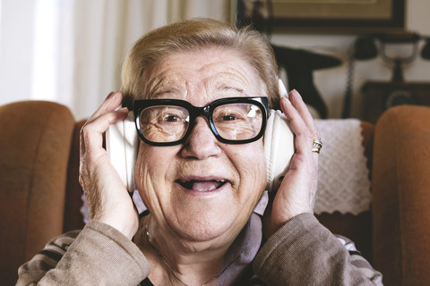 Porträt einer glücklichen älteren Dame, die mit Kopfhörern Musik hört, lizenzfreies Stockfoto