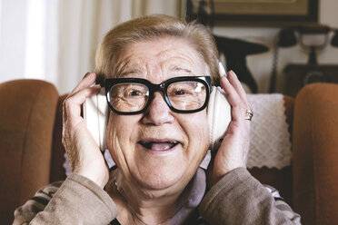 Portrait of happy elderly lady hearing music with headphones - GEMF000140