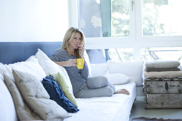 Relaxed woman sitting on couch with cup of coffee - MAEF009963