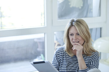 Portrait of woman using digital tablet at home - MAEF010002