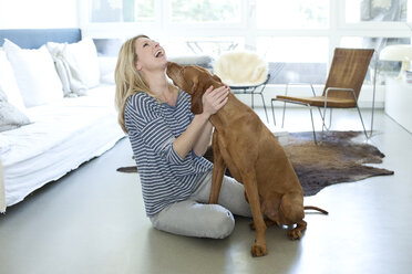 Woman playing with her dog at home - MAEF010017