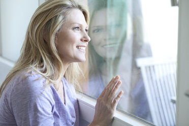 Blond woman looking through window - MAEF010037