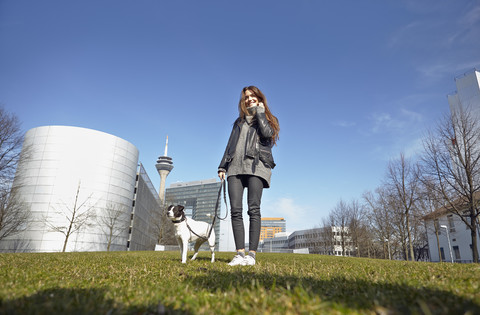 Deutschland, Düsseldorf, Junge Frau geht mit ihrem Hund spazieren, lizenzfreies Stockfoto