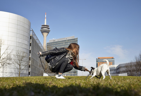 Deutschland, Düsseldorf, Junge Frau spielt mit ihrem Hund, lizenzfreies Stockfoto