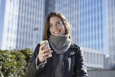 Deutschland, Dusseldorf, Junge Frau hält Smartphone - RHF000661