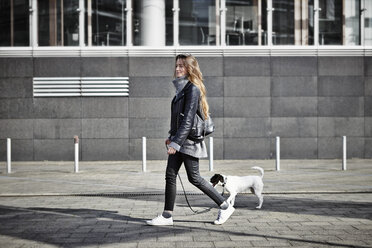 Germany, Dusseldorf, Young woman walking her dog - RHF000663