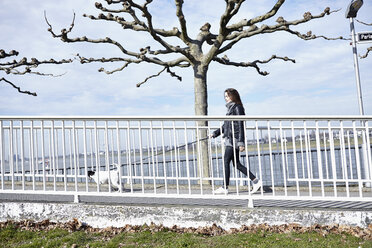 Deutschland, Düsseldorf, Junge Frau geht mit ihrem Hund spazieren - RHF000664
