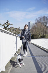 Germany, Dusseldorf, Young woman walking her dog - RHF000668