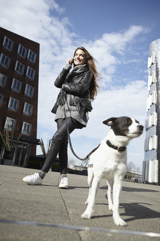 Deutschland, Düsseldorf, Junge Frau mit Hund und Smartphone, lizenzfreies Stockfoto