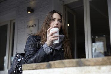 Deutschland, Düsseldorf, Junge Frau mit Kaffee im Freien sitzend - RHF000680