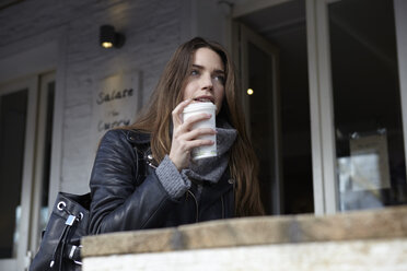 Germany, Dusseldorf, Young woman with coffee sitting outdoor - RHF000680