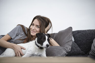 Junge Frau entspannt mit Hund auf Couch - RHF000713