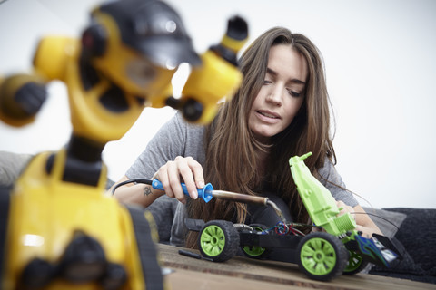 Junge Frau repariert Spielzeugauto, lizenzfreies Stockfoto