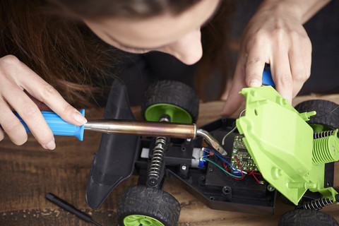 Junge Frau repariert Spielzeugauto, lizenzfreies Stockfoto