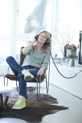 Woman hearing music with headphones at home - MAEF010043