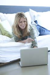 Frau entspannt auf Couch mit Laptop - MAEF010056