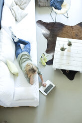 Woman relaxing on couch using laptop - MAEF010057