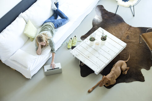 Woman relaxing on couch using laptop - MAEF010058