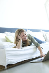 Woman relaxing on couch using laptop - MAEF010059