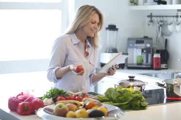 Frau mit digitalem Tablet beim Kochen in der Küche - MAEF010107