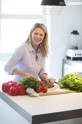 Lächelnde Frau beim Kochen in der Küche - MAEF010108