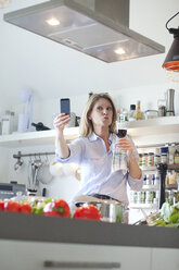 Woman in kitchen with glass of red wine taking a selfie - MAEF010157